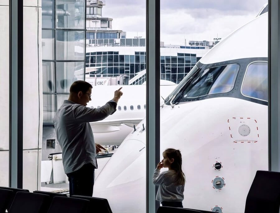 Family Pooling and Points Transfers: Comparing Every Major US Program 4 Father and daughter watching planes at an airport gate, representing family travel and pooled airline miles