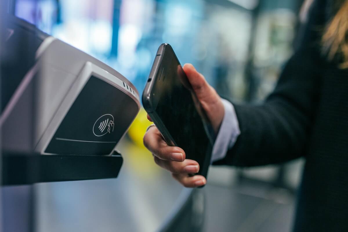 Priority Pass Restaurants and Digital Membership: What's Actually Still Included 5 Traveler tapping a phone at a contactless entry reader, similar to scanning a Priority Pass Digital Membership Card