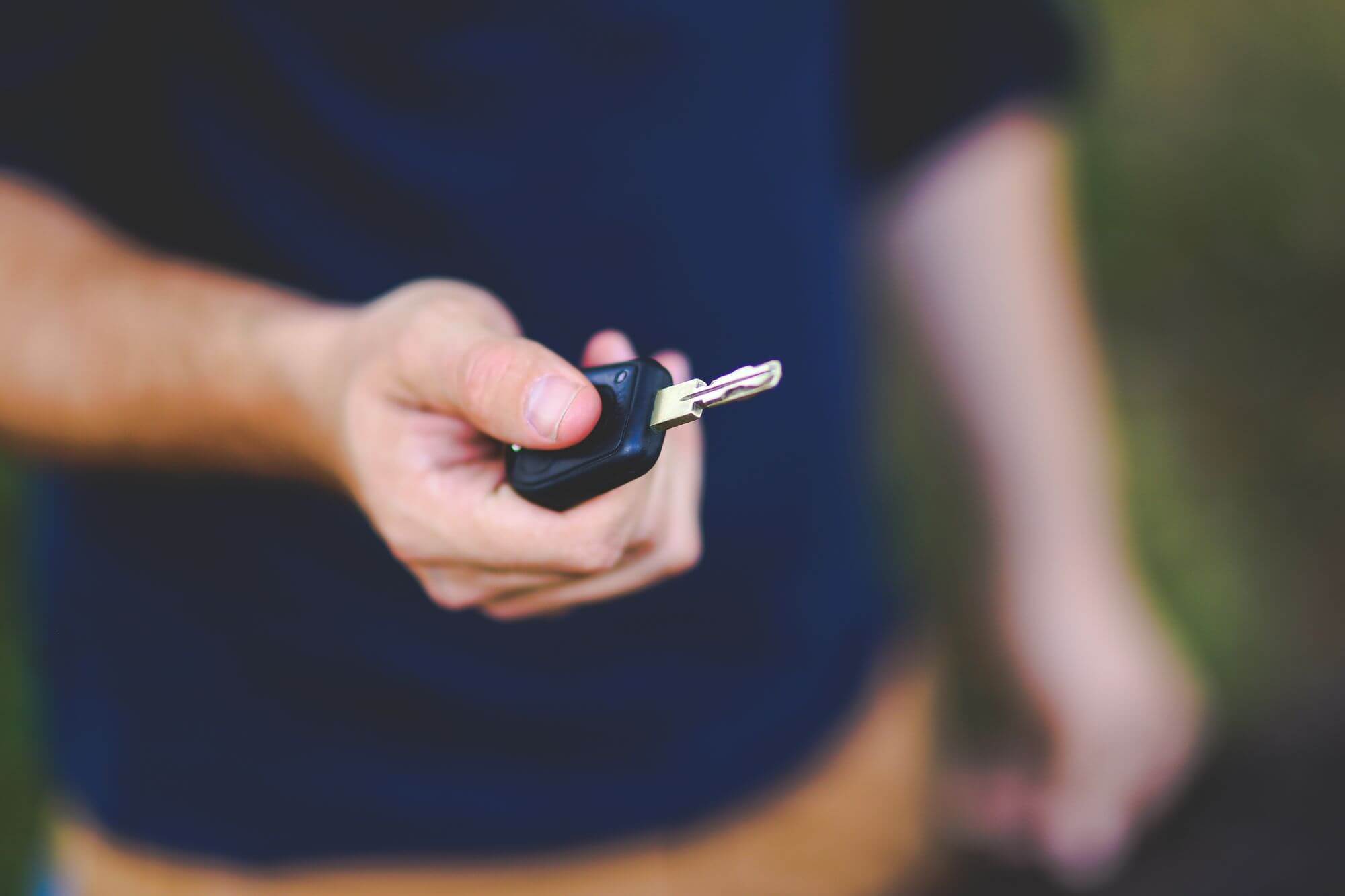 Close-up of a hand holding a car key outdoors