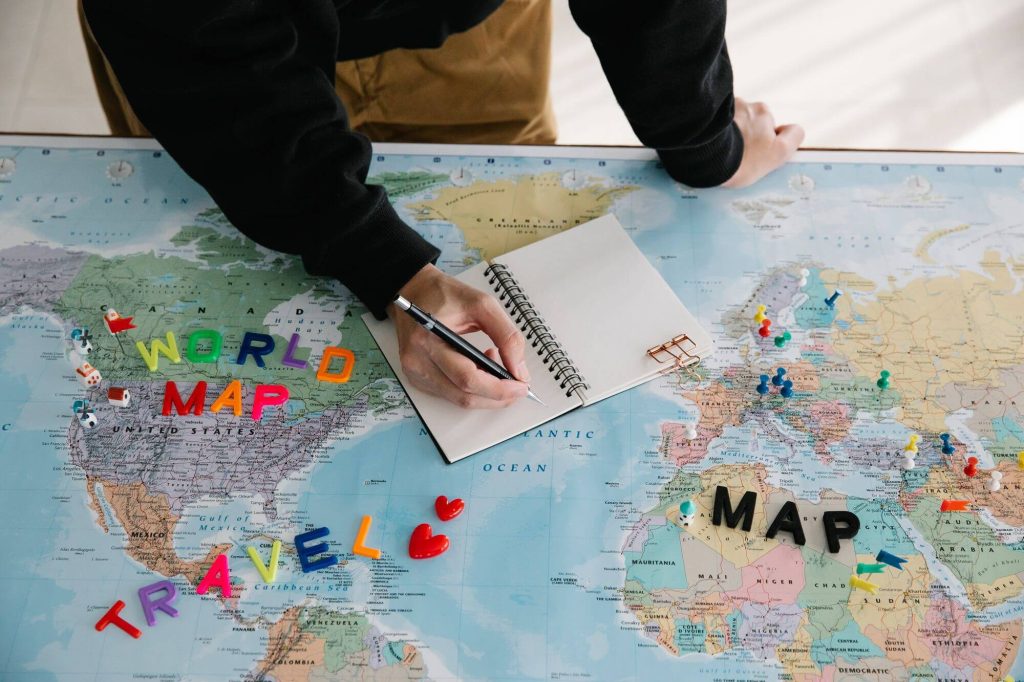 Person planning travel on a world map with a notebook