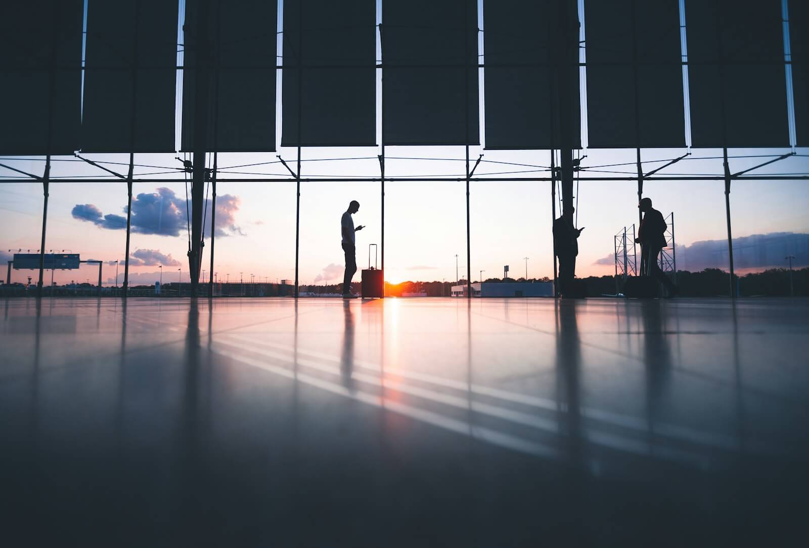 Travelers at airport terminal at sunset