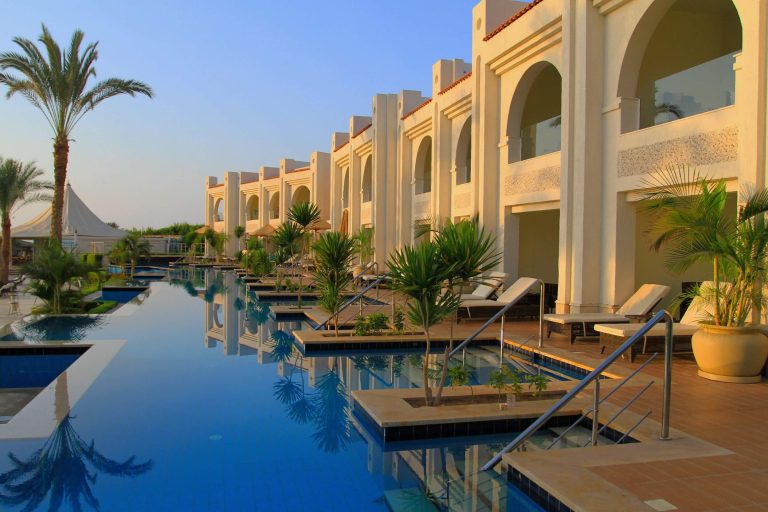 Upscale resort infinity pool with palm trees at golden hour