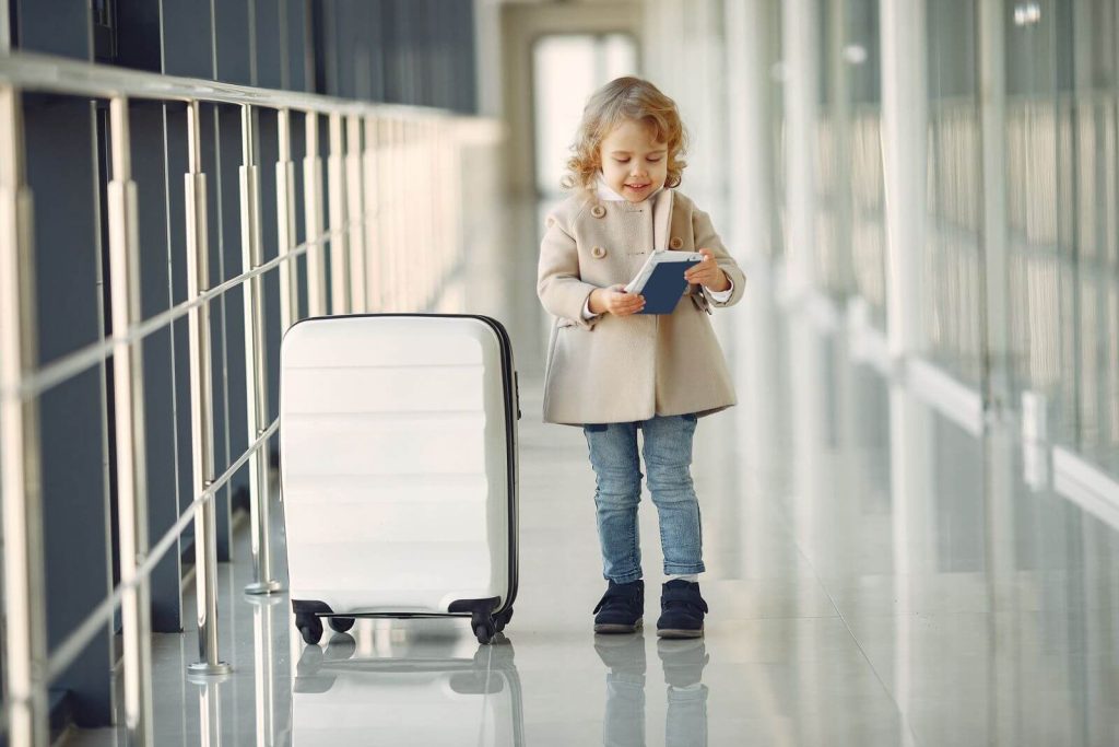 Young child with suitcase and passport in an airport corridor