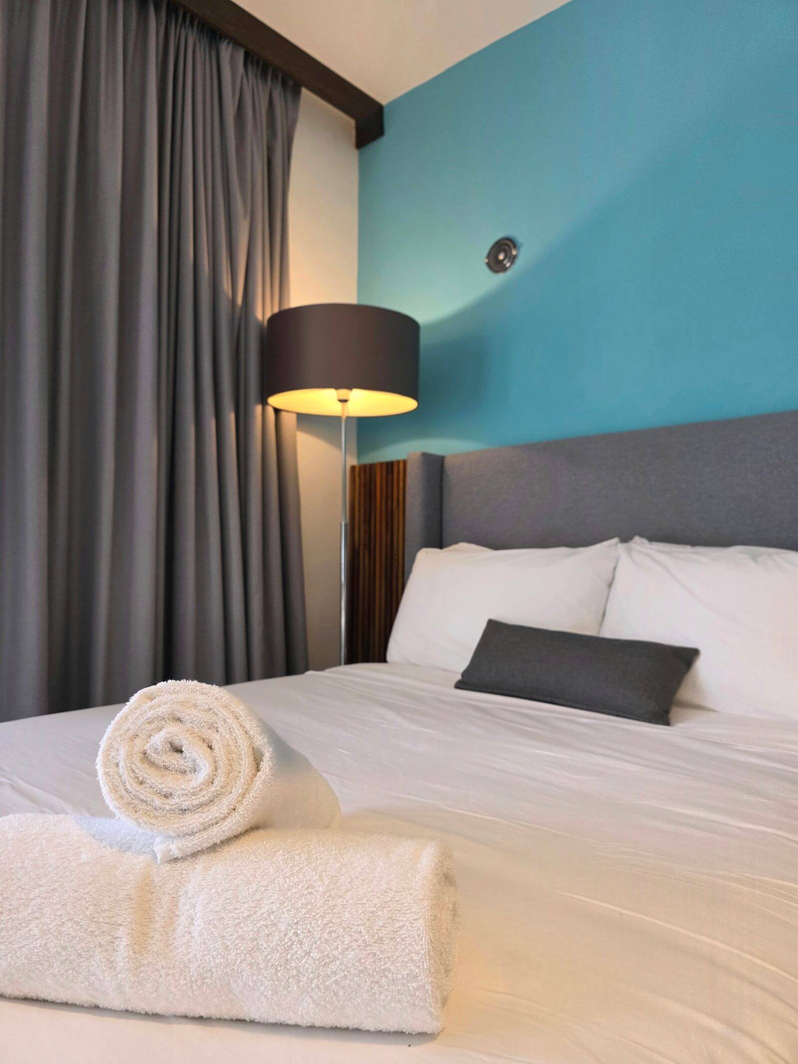 Wyndham Rewards Earner Card Review: Is a No-Fee Hotel Card Worth It? 4 Cozy hotel room bed with rolled towels
